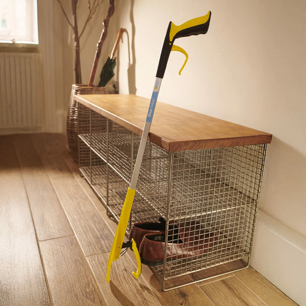 Helping Hand Shoe Helper on a wire shoe rack with wooden top, placed in a hallway with wood floors, side view.