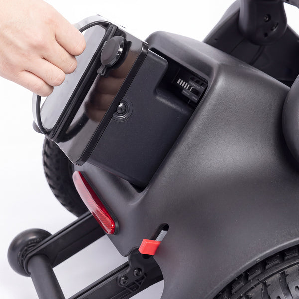 Hand opening battery cover on Urathon Hero Carbon Fibre Powerchair with airline-friendly battery, close-up view.