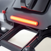 Red LED taillight on Urathon Hero Carbon Fibre Powerchair with frame and attachment visible, close-up.
