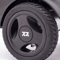 Urathon Hero Carbon Fibre Powerchair tyre with three-spoke hubcap and 7.2 logo, close-up.