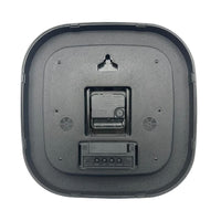 Robotic vacuum next to a Lifemax High Contrast Day-Date Wall Clock, battery compartment and openings visible, top angle.