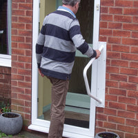 Homecraft Handy Rail used by an older adult for support at a doorway with steps, in use.