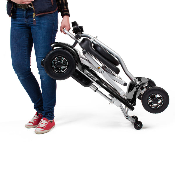 Person in jeans holding a Drive Instafold Folding Mobility Scooter by the frame, white background, in use view.