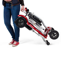 Person holding a folded Instafold Folding Mobility Scooter by Drive, white background, standing side view.