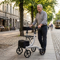 Older man using Integrity Leo Premium Rollator with adjustable handles, walking on sunny pavement, side view.