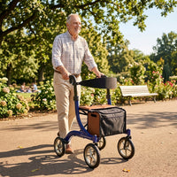 Elderly man using Integrity Taurus Premium Rollator by Integrity Mobility Solutions in park, trees and bench in background, in use.