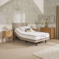 Opera Beds Jade Motion Adjustable Bed with wooden furniture and floral wallpaper, dresser decor in background, front view.