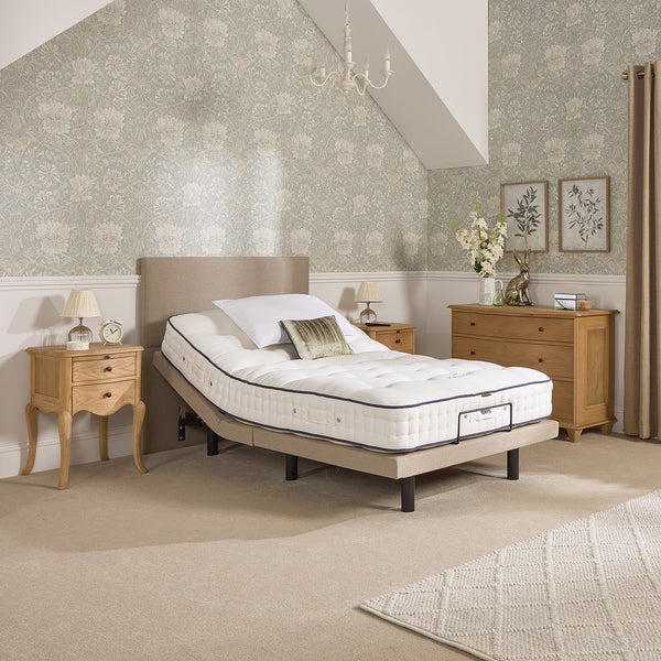 Opera Beds Jade Motion Adjustable Bed with wooden furniture and floral wallpaper, dresser decor in background, front view.