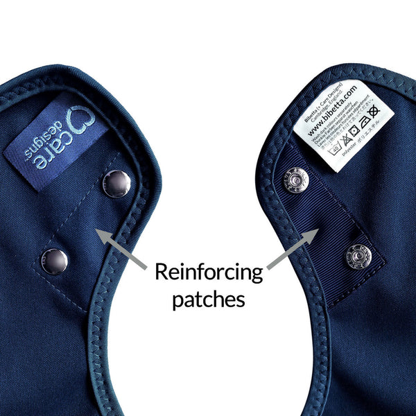 Care Designs Tabard Style Adult Bib with two metal snaps and reinforced patches by the fasteners, close-up view.