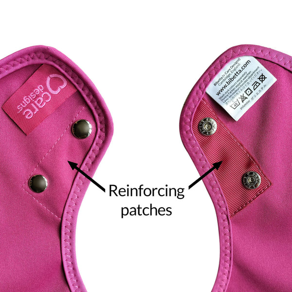 Care Designs Junior Tabard Style Bib with reinforced patches and metal snap buttons, text and arrows highlighting features, close-up.