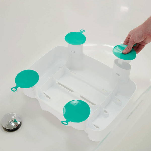 Hand attaching non-slip suction cup to Kingfisher Bath Seat by Helping Hand in bath near silver drain plug, close-up in use.