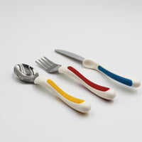 NRS Kura Care Children’s Cutlery Set with white handles, spoon, fork and knife on a plain background, front view.