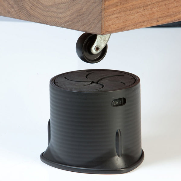 Langham SureGrip Furniture Raiser supporting wooden bed legs and securing under furniture wheels, in use view.