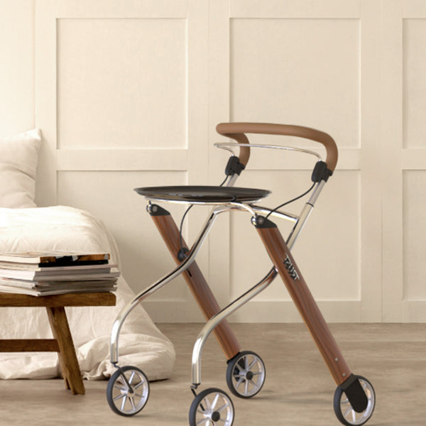 Trust Care Let’s Go Indoor Rollator next to a bed in a minimalist beige room, side view.