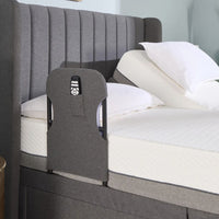 Opera Beds Motion Bed Grab Rail with remote pocket, attached to a bed with white bedding and pillows, side view.