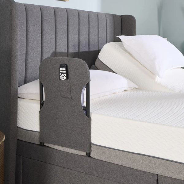 Opera Beds Motion Bed Grab Rail with remote pocket, attached to a bed with white bedding and pillows, side view.