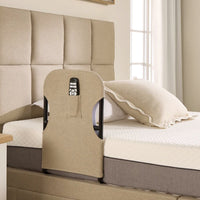 Opera Beds Motion Bed Grab Rail with fabric cover and remote pocket, next to an adjustable bed by a window, side view.