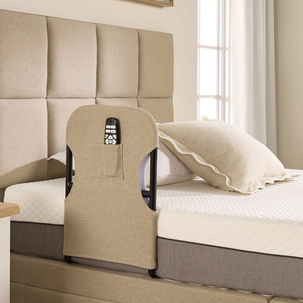 Opera Beds Motion Bed Grab Rail with fabric cover and remote pocket, next to an adjustable bed by a window, side view.