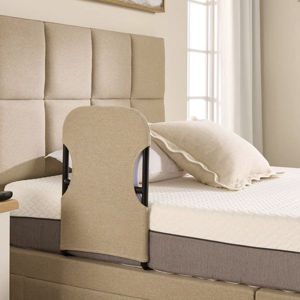 Adjustable bed with Opera Beds Motion Bed Grab Rail next to a window, white bedding and decorative pillow, side view.