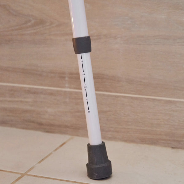 NRS Mowbray Lite Toilet Aid adjustable leg with height markings and rubber tip next to bathroom support rails, close-up.