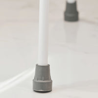 White metal leg with grey rubber tip from NRS Mowbray Lite Toilet Aid on shiny white floor, close-up.