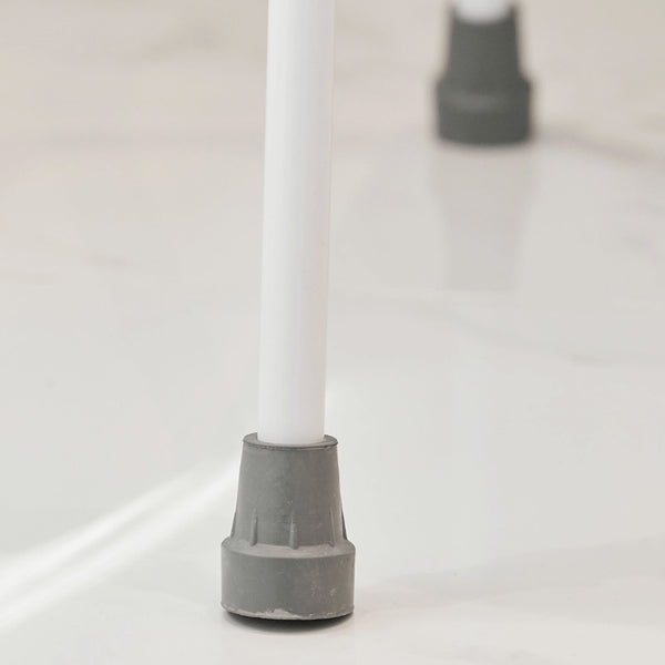 White metal leg with grey rubber tip from NRS Mowbray Lite Toilet Aid on shiny white floor, close-up.
