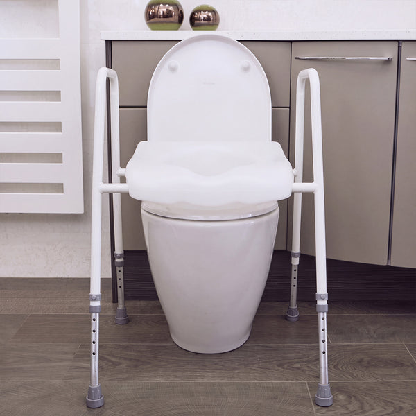 NRS Mowbray Lite Toilet Aid with handles and adjustable height next to modern bathroom cabinets, front view.