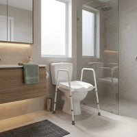 NRS Mowbray width-adjustable toilet seat in a modern bathroom, glass shower and floating vanity, towel and rug, wide view.