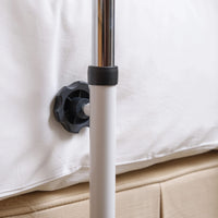 NRS Divan Overbed Table placed by a bed frame beside mattress and box spring, side view.