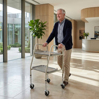 Older man using NRS Home Helper Wheeled Trolley in a bright lobby with large windows and plants, in use.