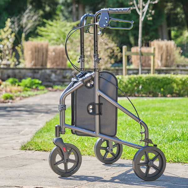 NRS Three Wheel Aluminium Rollator on a stone path, lightweight frame with three wheels for walking support, side view.
