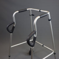 NRS Walk Safe Walking Frame with two front wheels and hand grips on a plain background, front view.