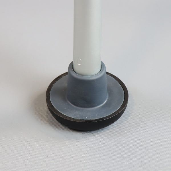 Rubber cap attached to the base of an NRS Walk Safe Walking Frame on a pale surface, close-up view.
