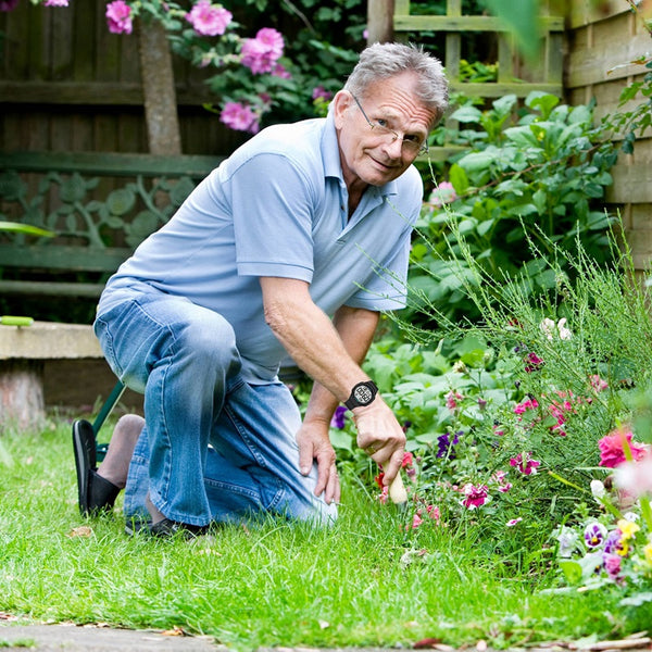 Older man gardening while wearing a Pivotell 8 Alarm Vibrating Watch, in use outdoor view.