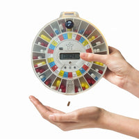 Pivotell Advance Automatic Pill Dispenser releasing pills into a hand, white background, front angle.
