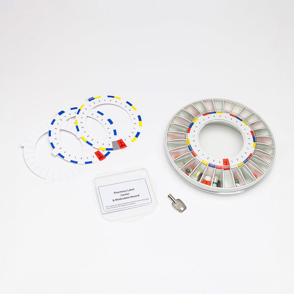Pivotell Mk3 Automatic Pill Dispenser with labels, spare disks, metal key and clear lid, front view.