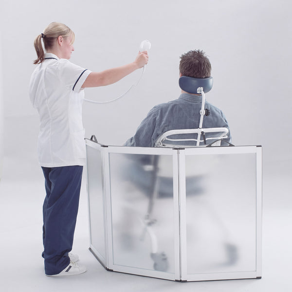 NRS Portascreen Shower Guard surrounding a seated patient being washed with a handheld shower by a nurse, in use view.