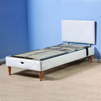 Restwell Devon Electric Adjustable Bed Base with wooden legs in a room with blue walls and beige carpet, front view.