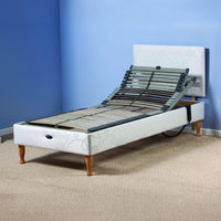 Restwell Devon electric adjustable bed with raised head on carpet, blue wall background, side view.