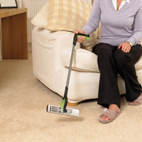 RevoReach GripLock used to pick up a remote from carpet next to sofa, in use.