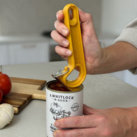 Easi-Grip Dext RingPull Can Opener opening a tin in a kitchen, tomatoes and garlic on chopping board nearby, in use view.