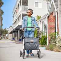Rollz Flex 2-in-1 rollator and shopping trolley in jungle green, used outdoors by an older woman with short grey hair, in use view.