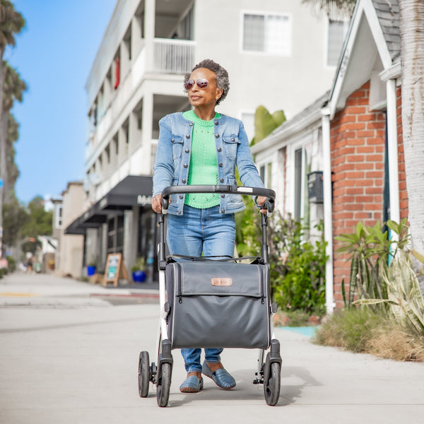 Rollz Flex 2-in-1 rollator and shopping trolley in jungle green, used outdoors by an older woman with short grey hair, in use view.