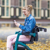 Person using Rollz Motion Performance all-terrain wheelchair while checking phone outdoors, in use view.