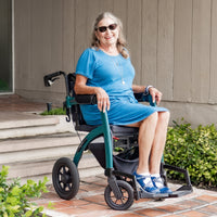 Woman in wheelchair with pneumatic tyres (Rollz Motion Performance) outdoors near steps and plants, side view.
