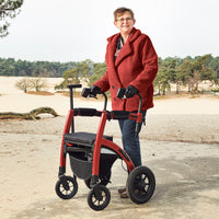 Woman in red coat outdoors using Rollz Motion Performance All-Terrain Rollator and Wheelchair, in use.