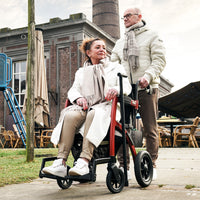 Rollz Motion Performance wheelchair with all-terrain tyres being pushed outside, in use, side view.