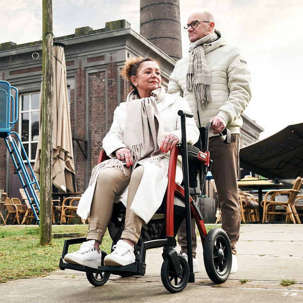 Rollz Motion Performance wheelchair with all-terrain tyres being pushed outside, in use, side view.