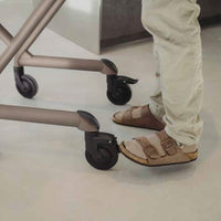 Person in beige sandals and trousers using the brake on a Saljol Indoor Rollator, in use view.