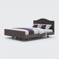 Opera Beds Signature Comfort Dual Profiling Bed with wheels, white bedding, and a curved headboard, side view.